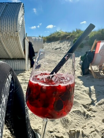 ein Erfrischungsgetränk am Strand, im Hintergrund Strandkörbe