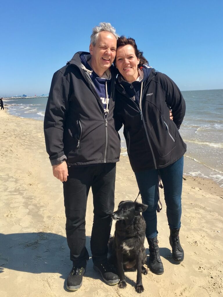 zwei Menschen, die sich umarmen und ein Hund dazwischen