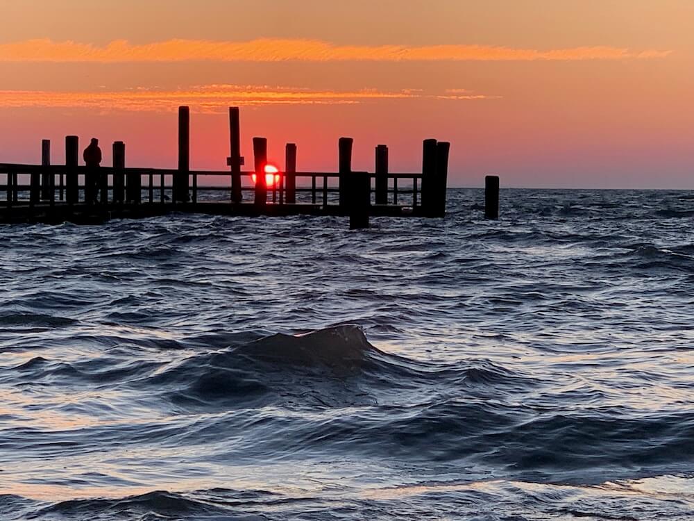 Die Nordsee und eine große Brücke dahinter geht die Sonne unter